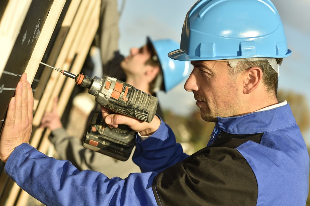 Construction worker using electric drill on building site-2